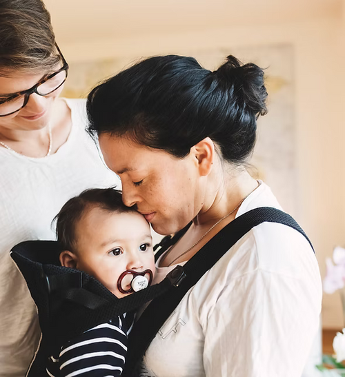 Woman holding a baby in a sling comfortably after a consultation with a private midwife on the sunshine coast